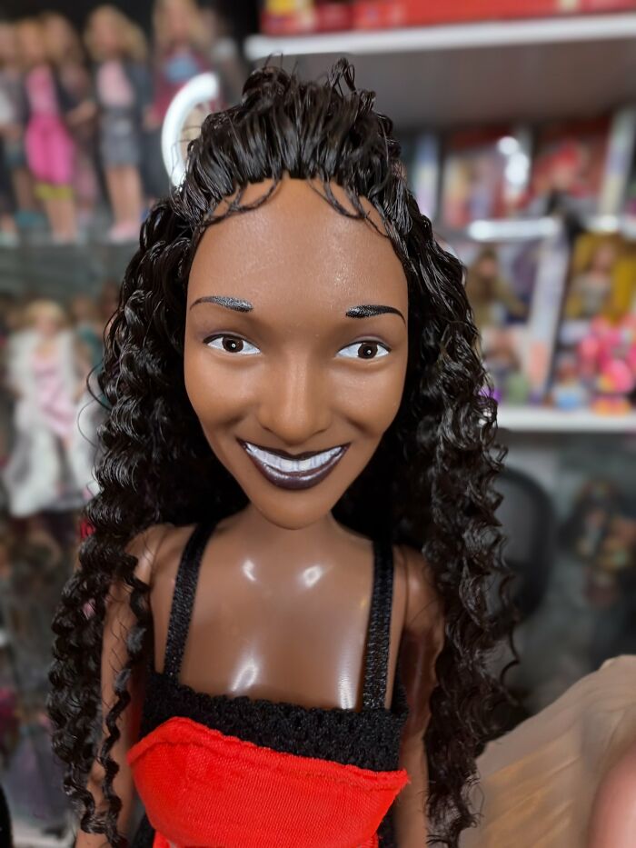 Close-up of an offensively ugly celebrity doll with curly hair and mismatched facial features in a display setting.