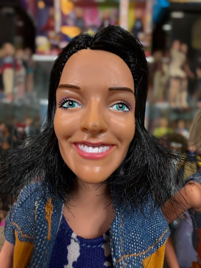 Close-up of an offensively ugly celebrity doll with uneven features and exaggerated smile on display.