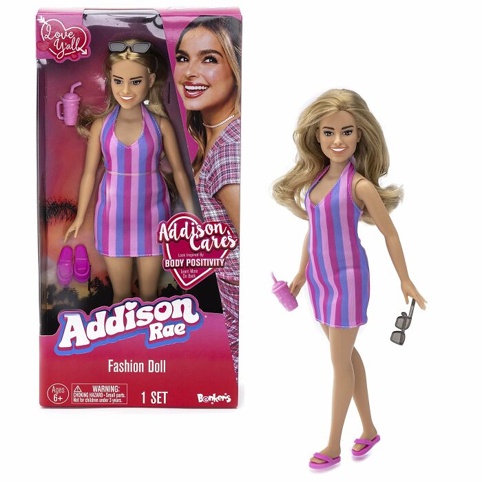Addison Rae celebrity doll in a pink and purple striped dress holding sunglasses and a drink, example of ugly celebrity dolls.
