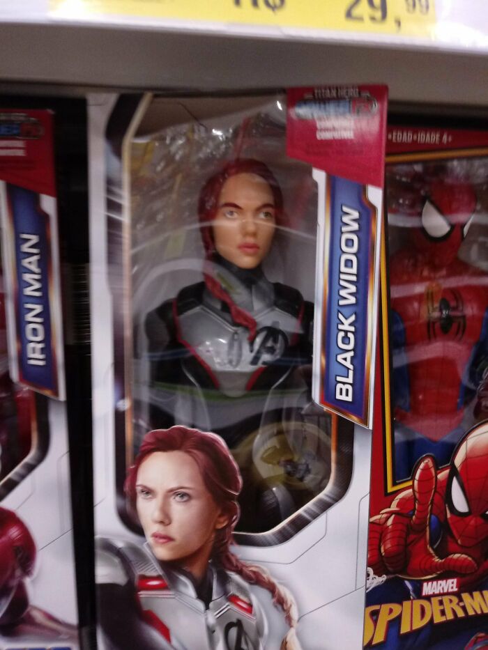 Black Widow celebrity doll with distorted facial features displayed in packaging among other Marvel action figures.