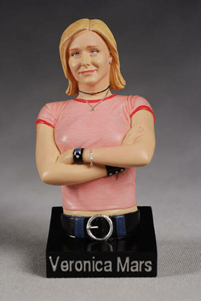 Offensively ugly celebrity doll bust of Veronica Mars wearing a pink shirt with crossed arms on a display stand.