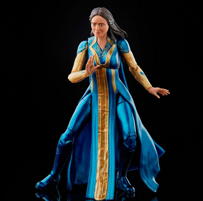 Uncomfortable looking celebrity doll wearing a blue and gold costume posed against a black background in a viral ugly celebrity dolls post.