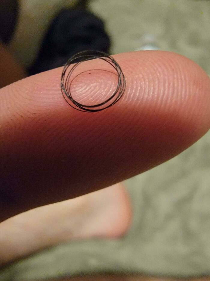 Close-up of a fingertip holding a tiny coiled hair loop in an unhinged moment that caught people off-guard.