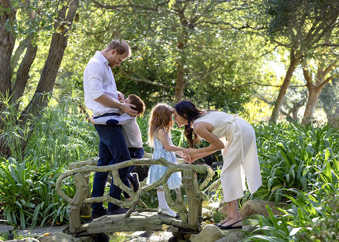 Family moment on a small bridge in a lush garden, highlighting Meghan Markle&rsquo;s alleged rift with mom Doria theories.