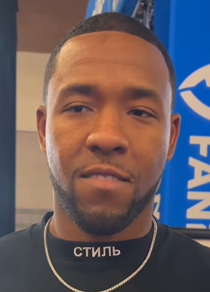 Budda Baker close-up portrait wearing a black shirt and silver chain, showcasing his style and confident expression.