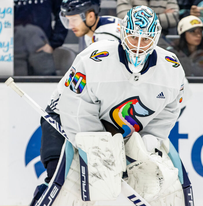 Martin Jones in white goalie gear and mask, focused on the game during a professional ice hockey match.