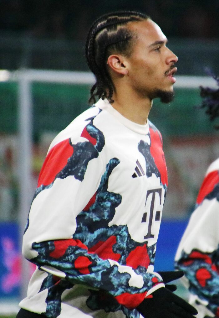 Leroy Sané wearing a patterned sports jersey during a warm-up session on a football pitch.