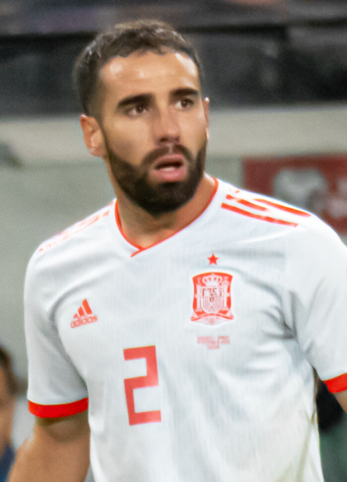 Dani Carvajal in Spain national team jersey during a football match, focused and actively playing on the field.