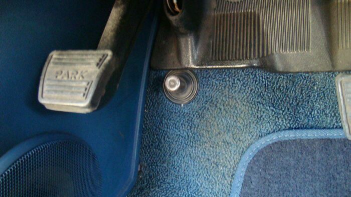 Close-up of a vintage car foot pedal labeled park, showing worn blue carpet, evoking nostalgia and feeling old as heck.