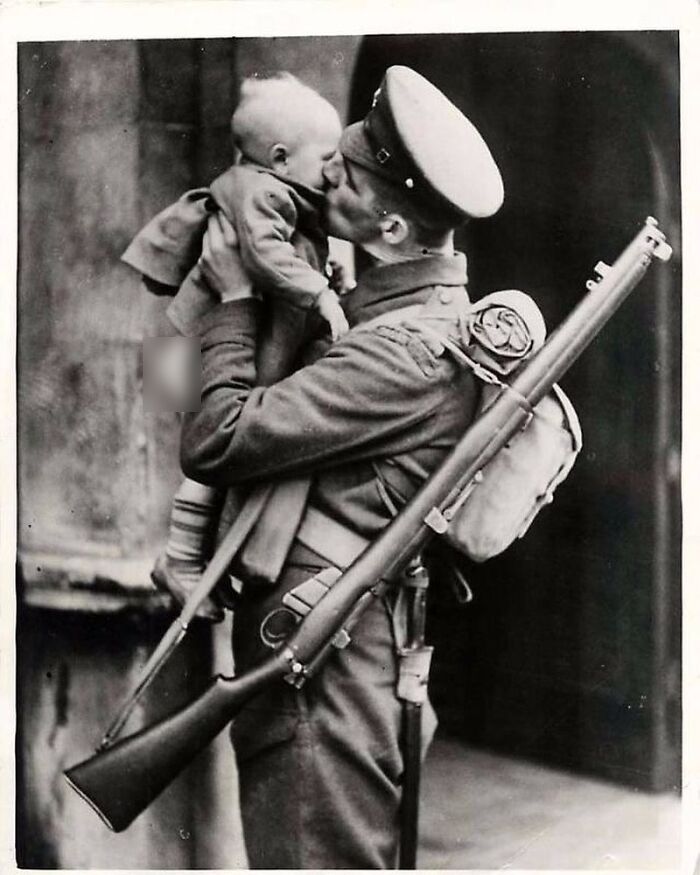 Soldier holding and kissing a baby, a poignant photograph reflecting the sad and beautiful history of humanity.