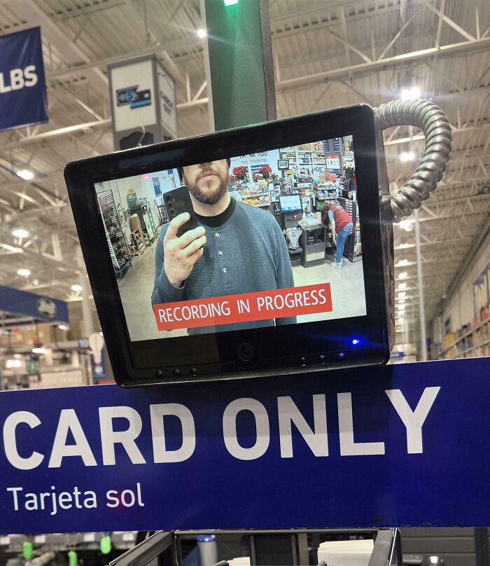 Surveillance screen showing tall person struggling to fit fully in frame at a checkout labeled card only.