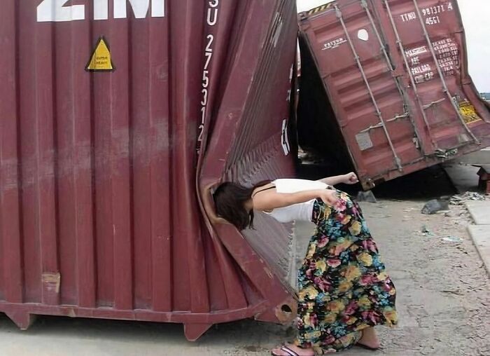 Woman with floral skirt bending her head inside a dented shipping container, creating a random and cringe photo moment.