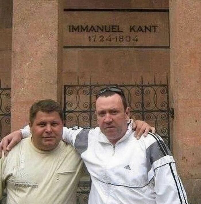 Two men posing in front of a historical building, a random and cringe photo for those with a unique sense of humor
