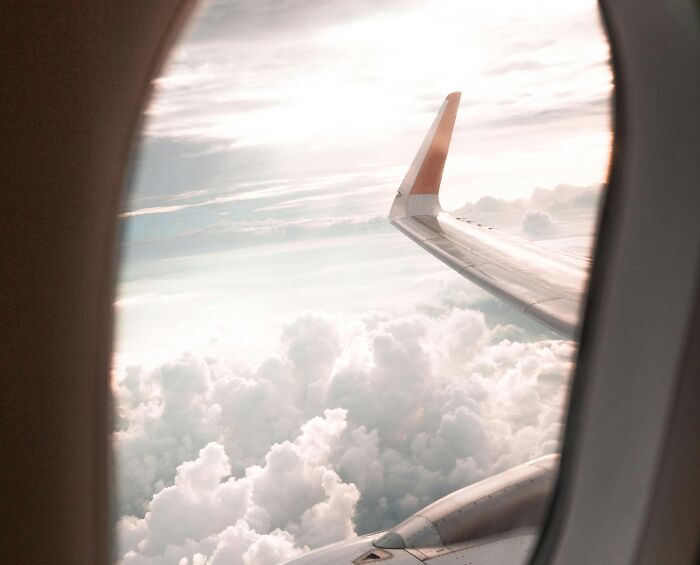 View of airplane wing and clouds from window symbolizing rich people’s out of pocket statements on living costs.