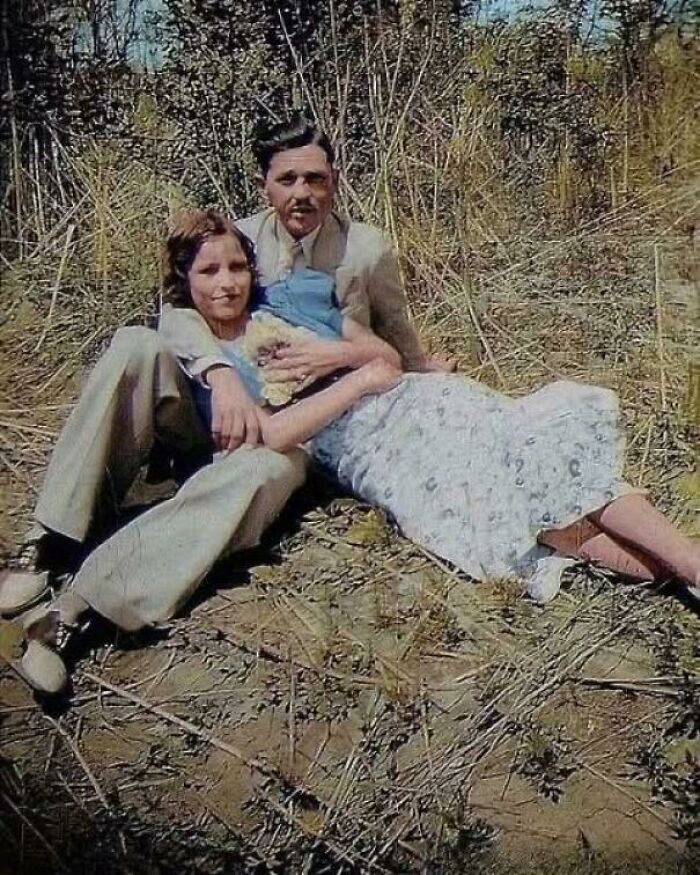 Couple sitting outdoors in old-fashioned clothes in a creepy old-school photo with a slightly cursed vibe.