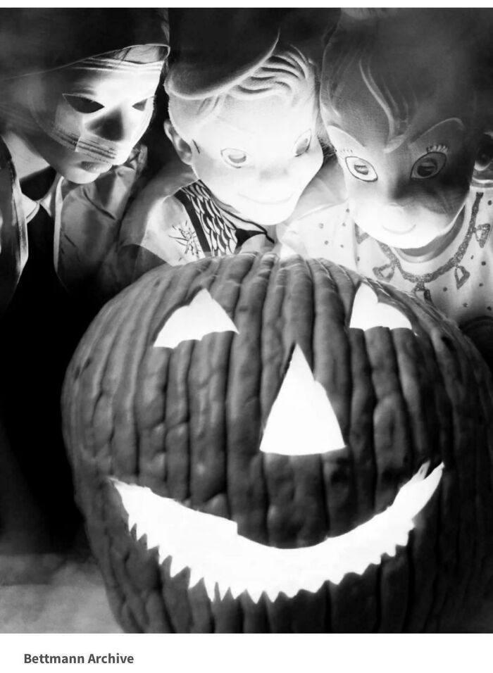 Three children in creepy old-school masks stare at a glowing jack-o'-lantern, evoking a slightly cursed vintage photo vibe.