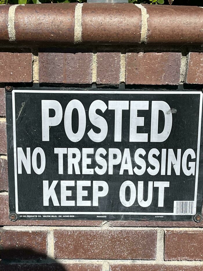 No trespassing sign on a brick wall illustrating practices that people in Europe may find weird compared to the US.