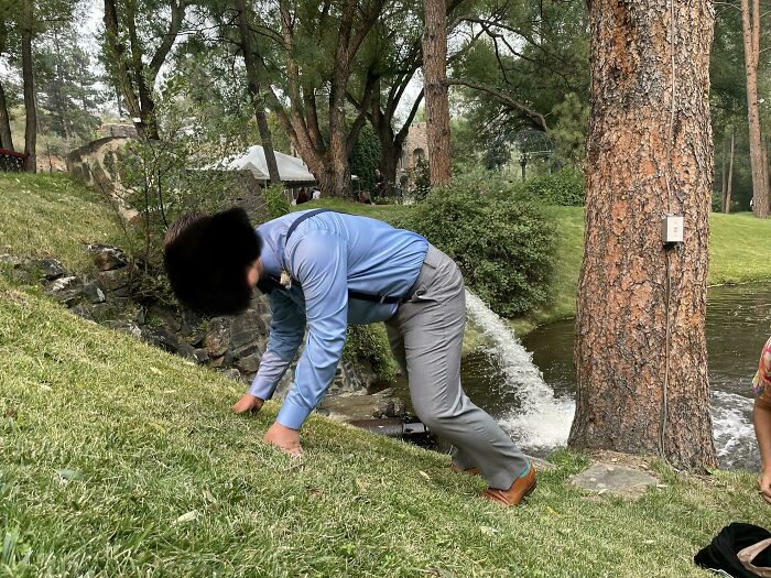 Hombre vestido formal resbalando en césped durante boda, foto de boda divertida y sorprendente con error legendario.