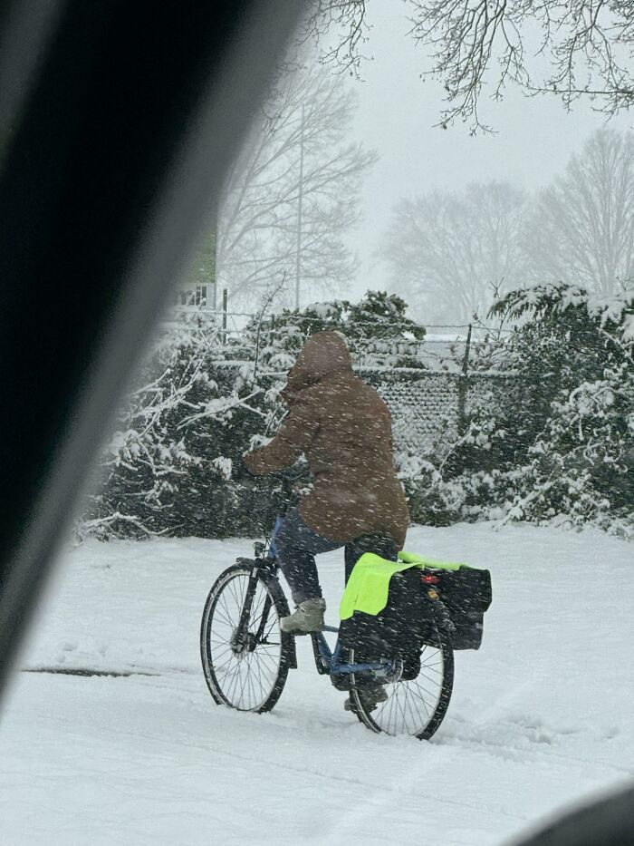 Person riding a bike through snowy winter landscape wearing warm clothing for a cozy winter scene.