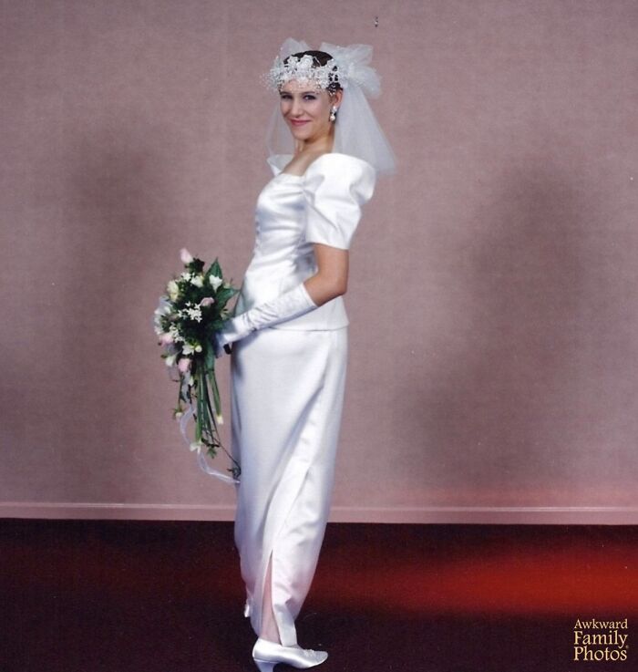 Bride in a vintage wedding dress and gloves posing awkwardly with a bouquet in an awkward wedding photo setting.