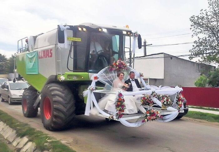 Novios sentados en una cosechadora decorada para boda, foto de boda divertida y legendaria.