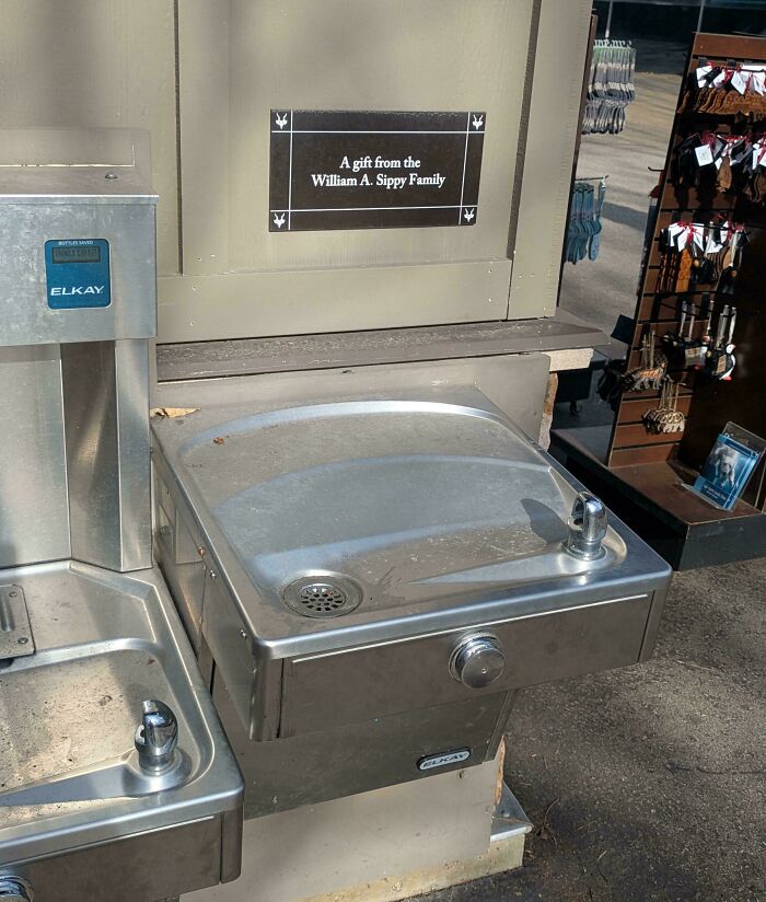Two stainless steel water fountains installed at different heights creating a confusing and funny visual contrast outdoors.