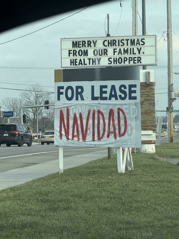 Confusing funny sign combining Christmas greeting with a for lease sign and a large red Navidad banner on a roadside.