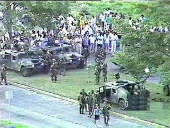 Military personnel and armored vehicles in a tense crowd scene related to unsettling history and crime incidents.