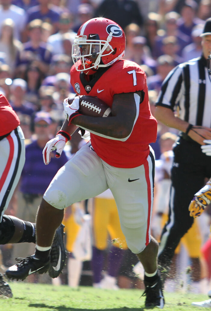 D'Andre Swift running with football in red Georgia Bulldogs uniform during a college football game on the field
