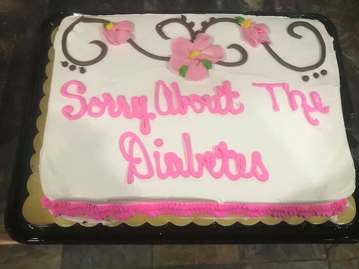 Humorous cake with pink icing and floral decoration displaying a funny message about diabetes and honest emotions.