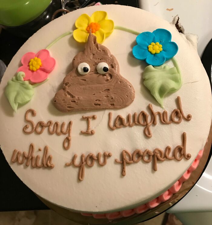 Round funny cake with a p**p emoji and colorful flowers, decorated with a humorous message about honest emotions.