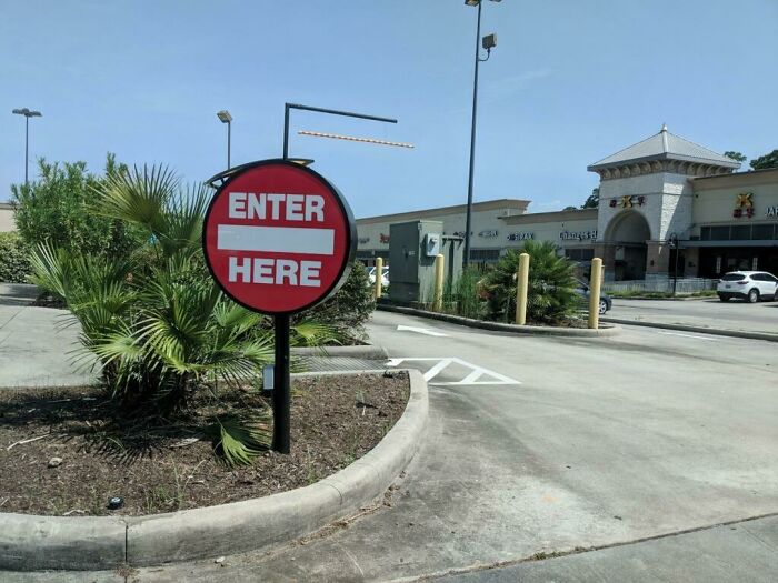 Confusing traffic sign showing enter here with a no entry symbol in a parking lot, illustrating terrible product design.