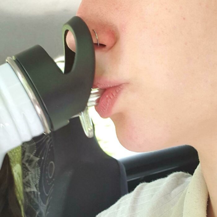 Person drinking from a water bottle with a terrible product design that obstructs easy sipping.