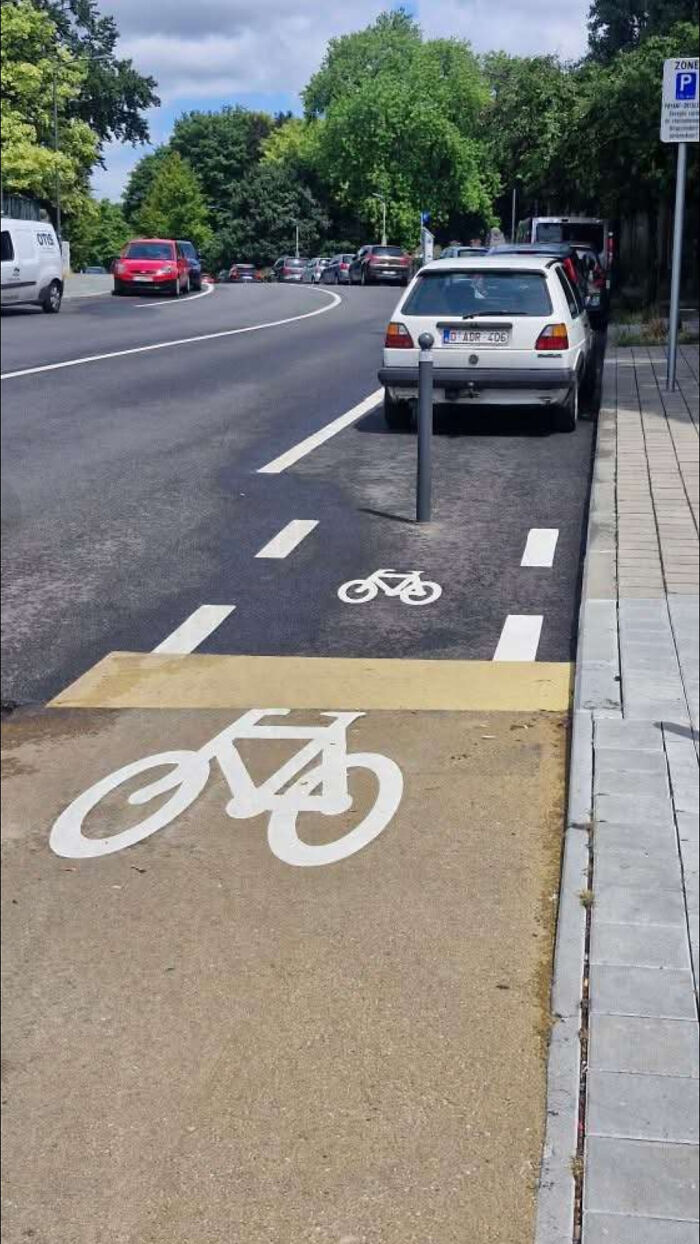 Bike lane with a pole blocking the path and a car parked on it, showing a terrible product design mistake outdoors.