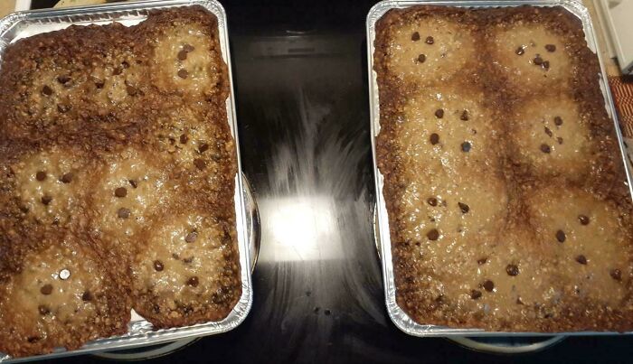 Two aluminum trays with overbaked and ruined dessert featuring unevenly melted chocolate chips.