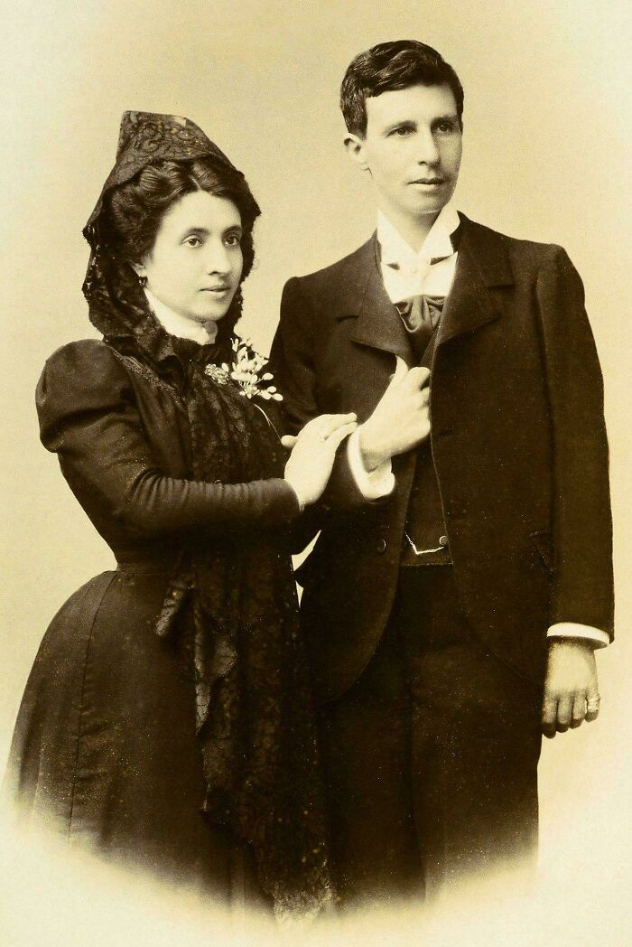 Victorian era couple in formal attire posing for a vintage portrait showing distinct fashion of the time period.