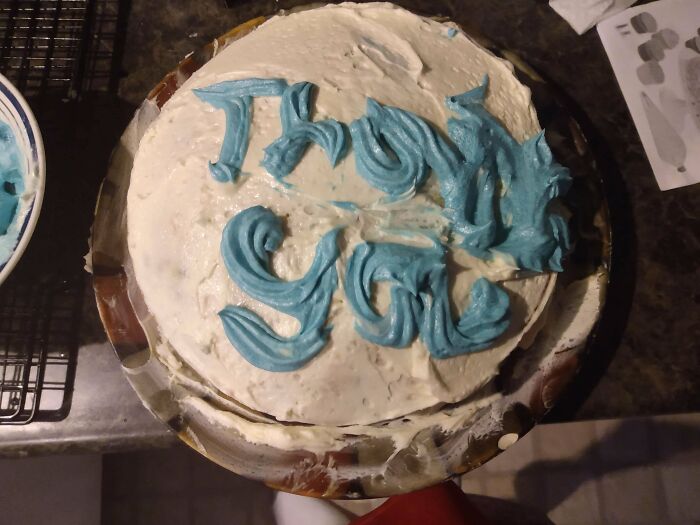 Cake with uneven frosting and poorly piped blue icing text as an example of ruined dessert decoration failure.