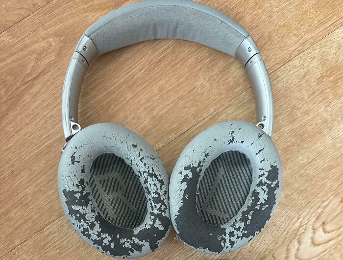 Worn down headphones with c*****d and peeling ear cushions showing signs of everyday object wear.