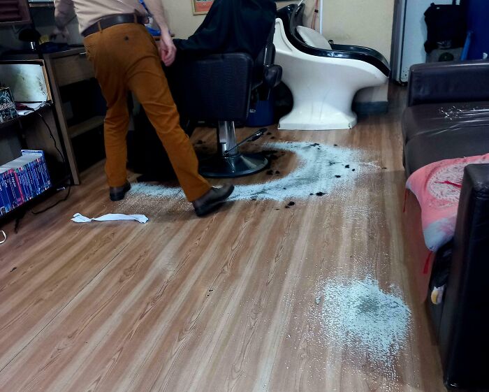 Worn down floor around a barber chair showing everyday objects worn down in unexpected ways.