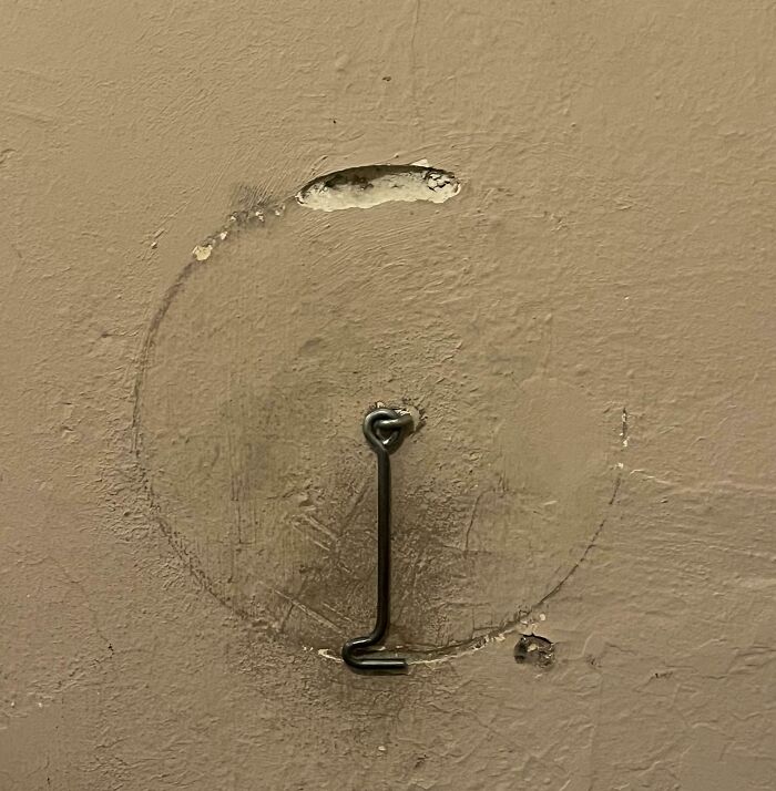 Worn down wall area showing circular marks and a bent metal hook, illustrating everyday objects wearing down unexpectedly.