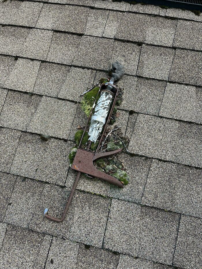 Rusty metal clamp with peeling paint and moss growing through it, showing worn down everyday objects in unexpected ways.