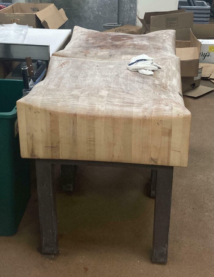 Worn down butcher block with deep indentations from heavy use in a busy kitchen environment.
