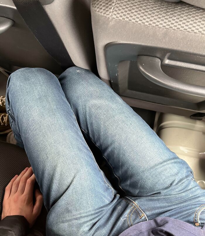 Person with long legs sitting uncomfortably in a small car space, illustrating struggles only tall people face.