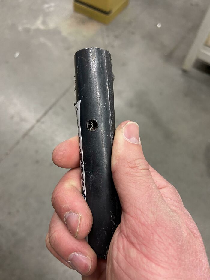 Hand holding black plastic tube with stripped s***w hole, an example of an unfortunate and stupid fail.