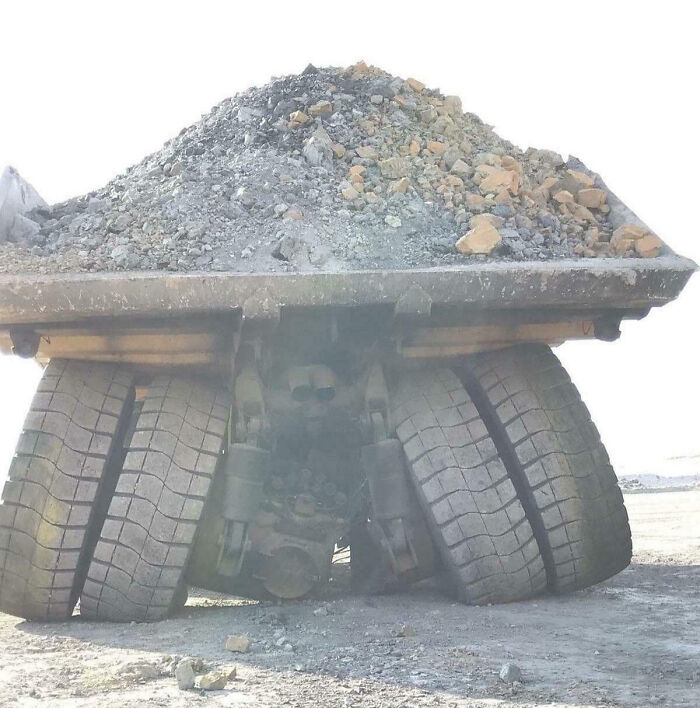 Heavy dump truck with unevenly loaded rocks causing tires to tilt, showcasing an unfortunate and expensive fail.