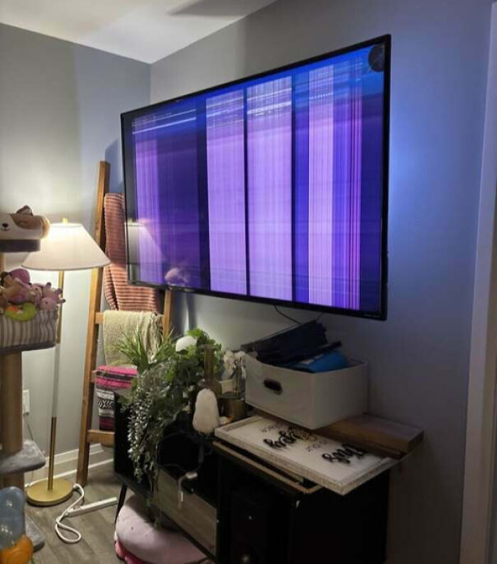 Broken TV screen mounted on wall showing distorted purple and blue lines, an unfortunate and expensive fail.