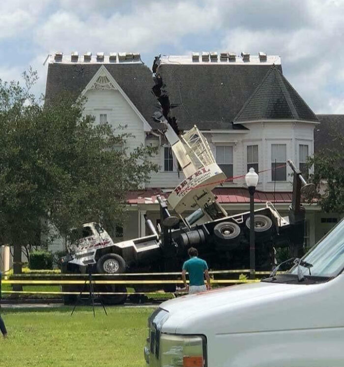 Crane truck crashed into a house causing a large split in the roof, illustrating an unfortunate and expensive fail.