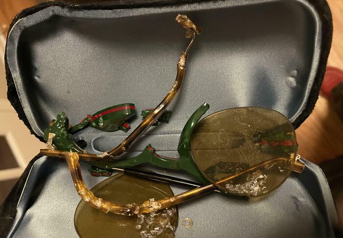 Broken green and gold sunglasses with c*****d lenses and twisted frame inside a black case showing expensive fails.