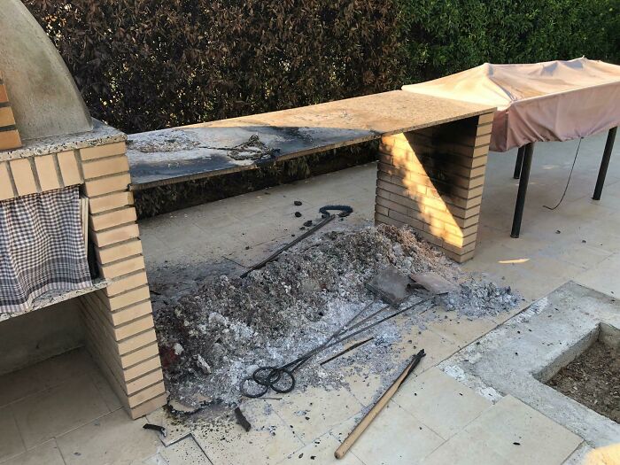 Outdoor grill area with a burnt and messy barbecue pit, showcasing an unfortunate and expensive fail.
