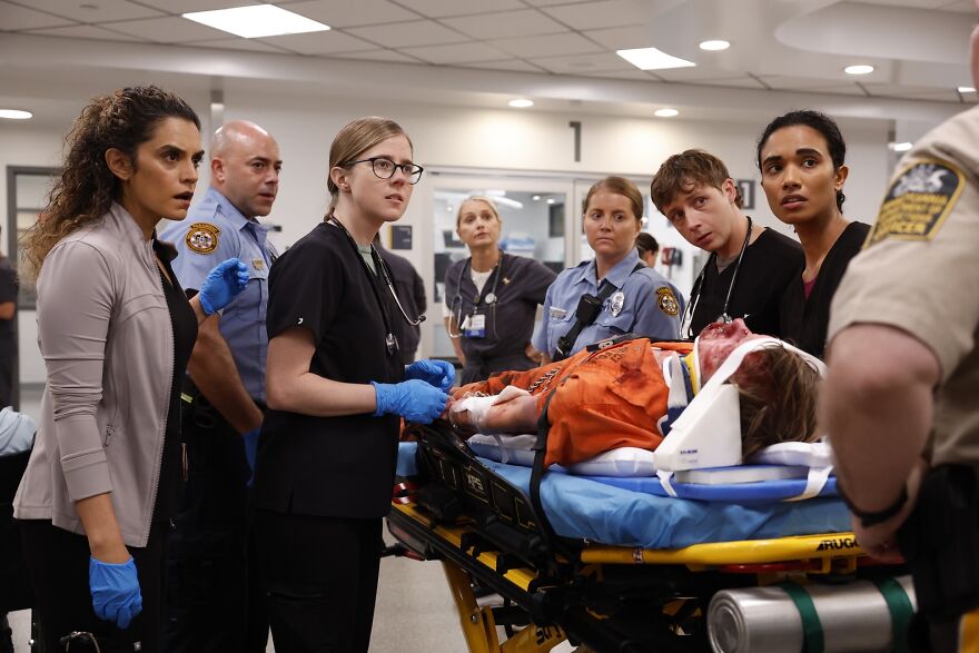Cast members and emergency staff in a hospital emergency room scene from The Pitt fans discussing famous father presence.